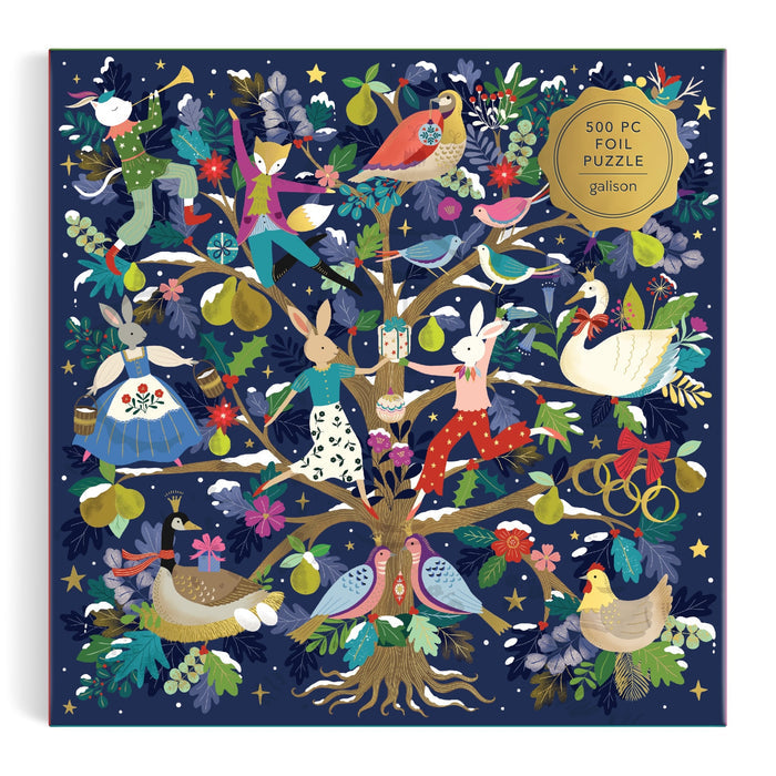 The 12 Days of Joy 500 Piece Foil Puzzle by Flora Waycott features animals like rabbits, birds, ducks, and a swan in festive outfits around a fruit and flower tree, adorned with stars. Box labeled: "500 Piece Foil Puzzle.