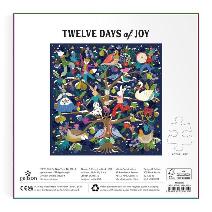 A vibrant illustration of a tree with playful birds, butterflies, and ornaments shines on a dark blue starry background. "12 Days of Joy 500 Piece Foil Puzzle" by Flora Waycott features the title above and a puzzle piece on the right.