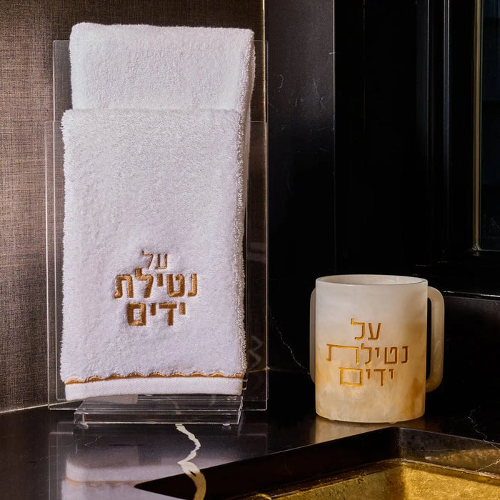 Al Netilas Yadayim ombre resin washing cup in cream and gold tones displayed with matching soap dispenser on dark vanity.