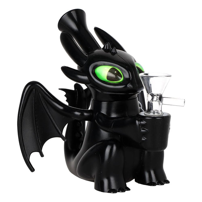 A black dragon figurine with glowing green eyes holding a clear glass water pipe, set against a plain white background.