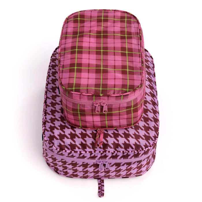 2 recycled nylon zippered packing cubes, large bag is pink and brown houndstooth, smaller bag is pink tartan, stacked on a white background.