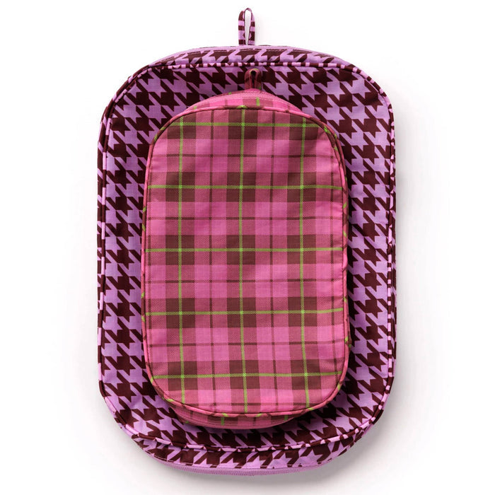2 recycled nylon zippered packing cubes, large bag is pink and brown houndstooth, smaller bag is pink tartan, flat and stacked on a white background.