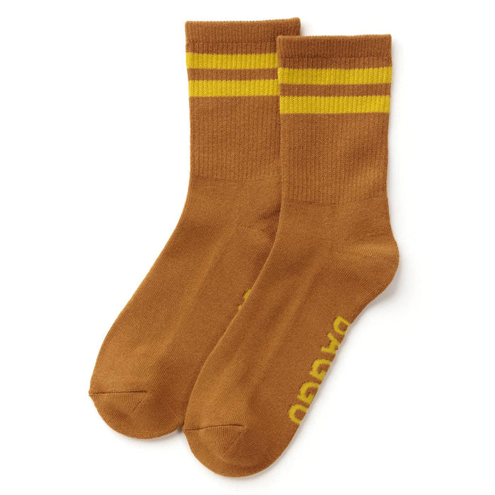 A pair of brown crew socks with two yellow stripes near the cuff and yellow branding printed on the sole, displayed on a clean white background.