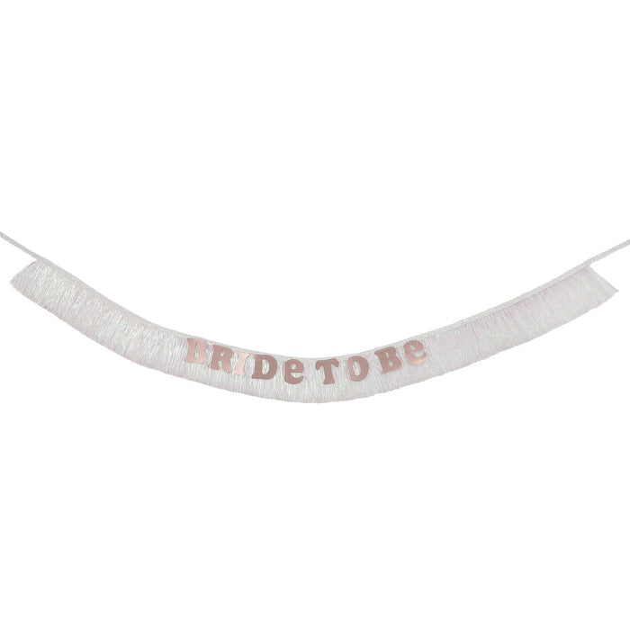 An iridescent white fringe sash with the words 'BRIDE TO BE' in shiny rose gold letters, suspended against a plain white background.