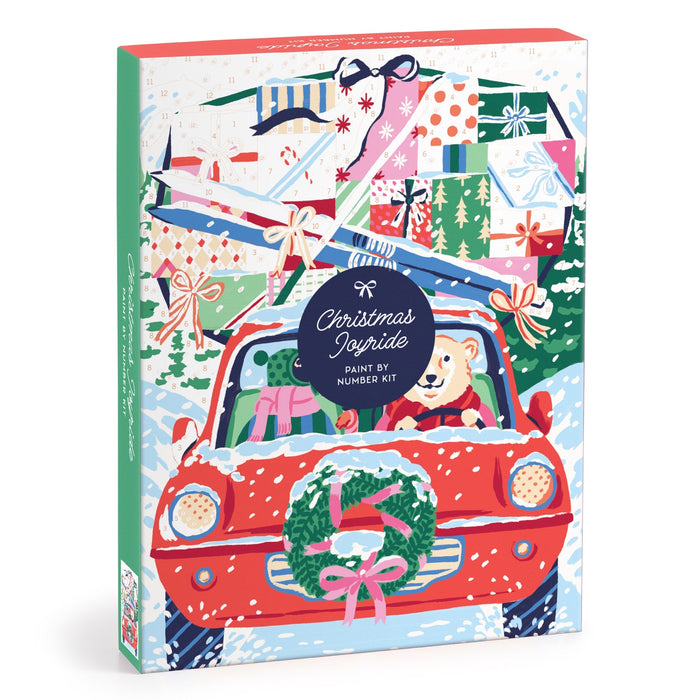 The Emily Taylor Christmas Joyride 9 x 12" Paint by Number Kit features a red car with a bear driver, wreath on the grille, presents and skis on the roof, all set against a snowy holiday background.