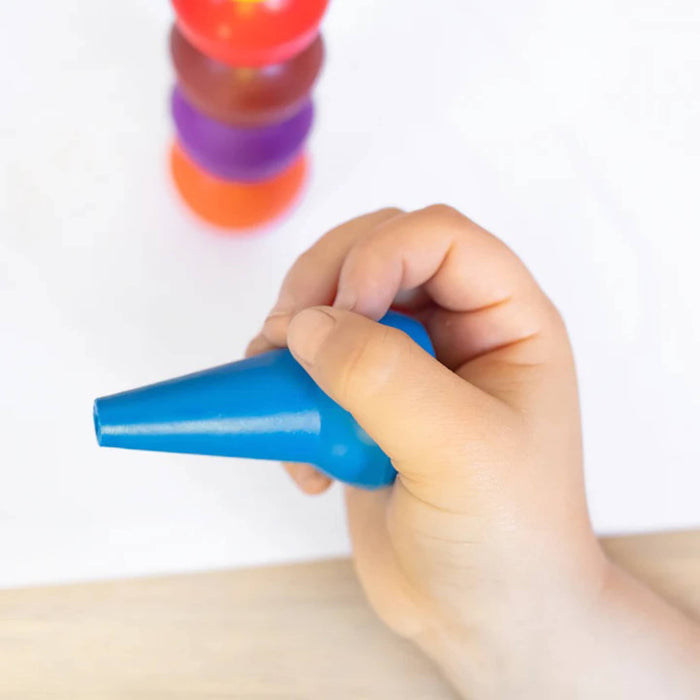 Hand holding a blue crayon with other color crayons stacked in the background.