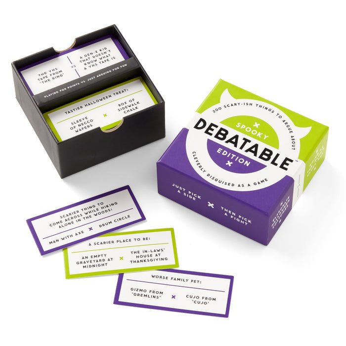 A box of Brass Monkey’s Debatable Spooky Edition, the ultimate spooky debate game, sits open with cards featuring prompts like “Scariest thing to encounter in the woods” and “Worse family pet.” Halloween cards are spread out beside it.