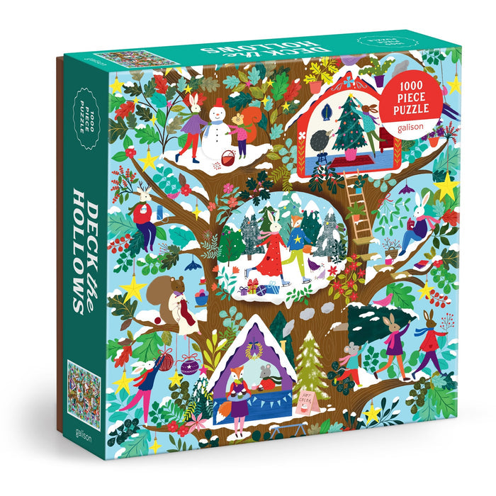The Deck the Hollows 1000 Piece Puzzle by Flora Waycott features an illustrated winter scene with animals and people decorating treehouses, building snowmen, and celebrating in a snowy forest.