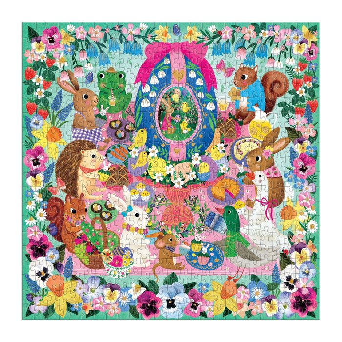 The Egg-cellent Day 500 Piece Foil Family Puzzle by Rebecca Jones showcases adorable rabbits, squirrels, a hedgehog, and a frog near a decorated egg and spring flowers, framed by a brilliant floral border.