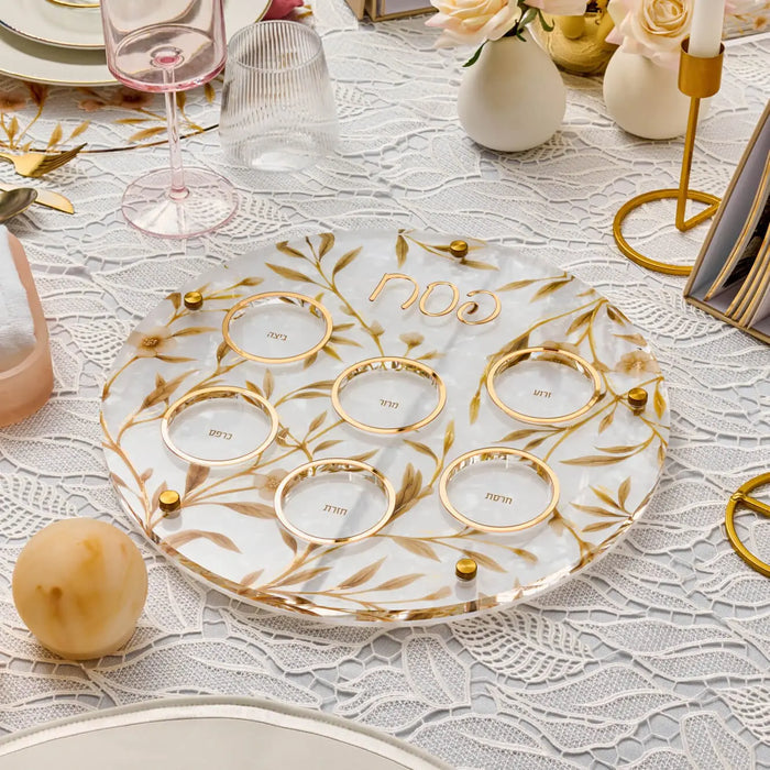 Floral Bird Seder Plate with gold leaf design on white lucite, displayed with Passover tableware and decorations.