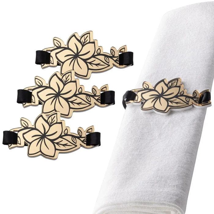Four gold floral napkin wraps with black bands arranged on white napkin, showing detailed flower designs from Waterdale Collection.
