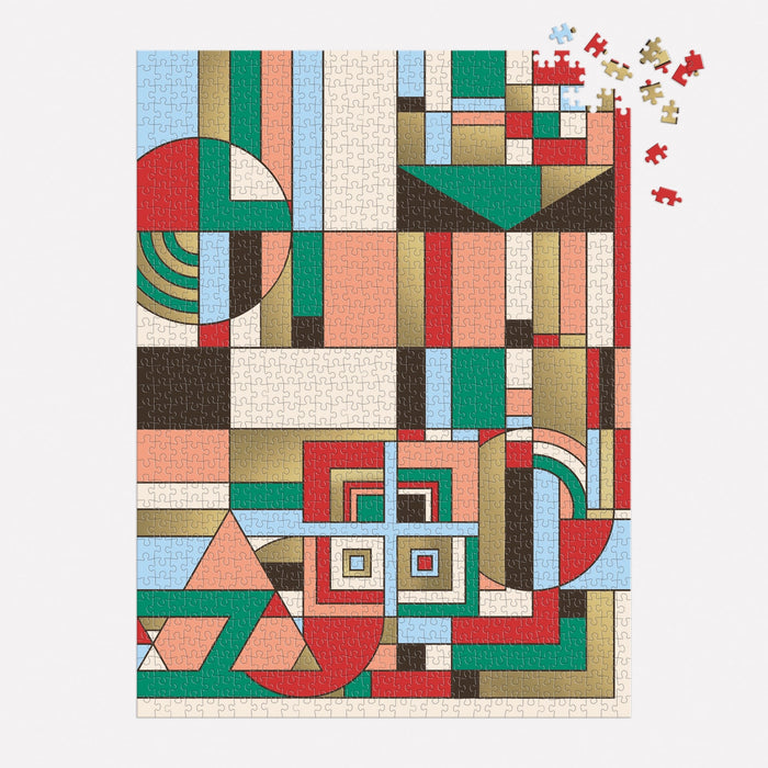 A nearly completed Frank Lloyd Wright December Gifts 1000 Piece Foil Puzzle by the Frank Lloyd Wright Foundation, featuring an abstract geometric design in red, green, beige, brown, blue, and cream. A few pieces remain unfinished in the top right corner.