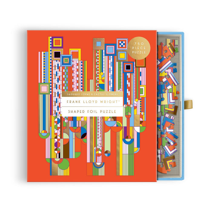 The Frank Lloyd Wright Foundation’s Saguaro Forms & Cactus Flowers 750 Piece Shaped Foil Puzzle features a vibrant orange box with geometric patterns and a partially open lid revealing assorted pieces inside.