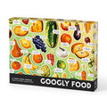The Brass Monkey Googly Food 1000 Piece Puzzle features illustrated fruits and veggies with googly eyes and witty bubbles on a light green background. The box includes 1,000 pieces.
