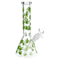 Clear glass beaker-style water pipe with a tall neck and side port, decorated with green cannabis leaf patterns, shown on a white background.