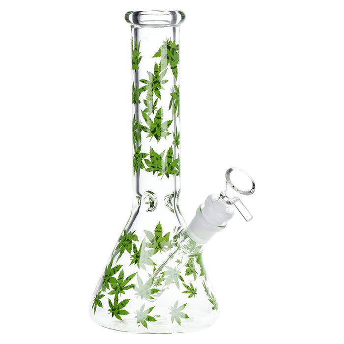 Clear glass beaker-style water pipe with a tall neck and side port, decorated with green cannabis leaf patterns, shown on a white background.