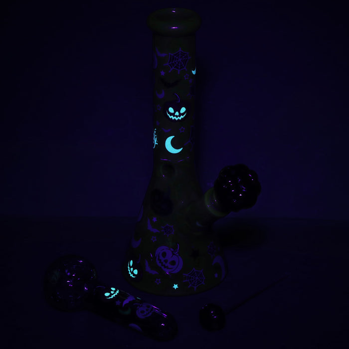 Glowing black glass pipe with Halloween-themed designs on a dark background
