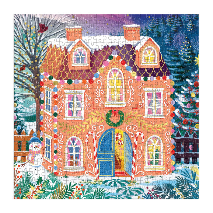 The Joanna Clay "Home Sweet Holidays" 500 Piece Foil Puzzle depicts a gingerbread-style house with holiday lights, a wreath, candy canes, snowy trees, and a decorated Christmas tree.