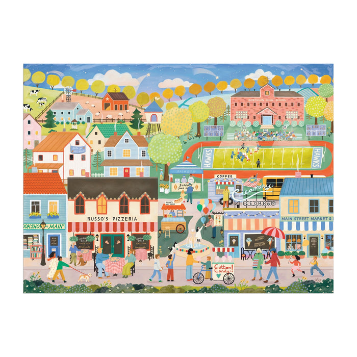 The Hometown Cheer 1000 Piece Puzzle by Elisabeth Dorrian features a vibrant small town scene with shops, restaurants, a pizzeria, people enjoying various activities, yellow-leaved trees, and a football game on a green field.