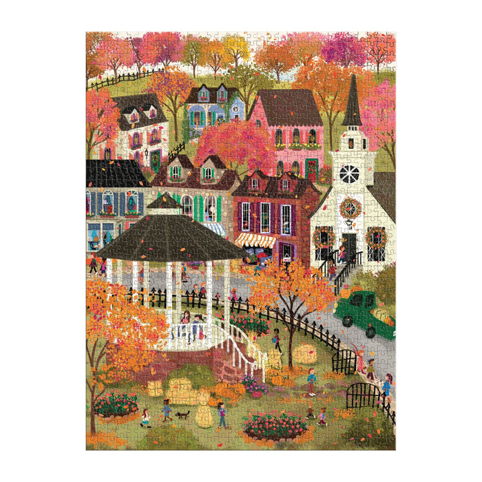 The Joy Laforme Falls Hollow 1000 Piece Puzzle by Joy Laforme features a vibrant autumn village with colorful trees, houses, a white steeple church, gazebo, and people enjoying the park paths among beautiful fall foliage.