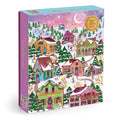 The Joy Laforme Snowcap Village 1000 Piece Foil Puzzle features a festive winter village with snow-covered houses, decorated trees, ice skaters, and a starry night sky with a crescent moon.