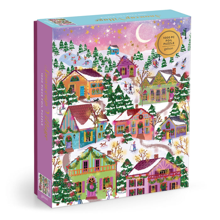 The Joy Laforme Snowcap Village 1000 Piece Foil Puzzle features a festive winter village with snow-covered houses, decorated trees, ice skaters, and a starry night sky with a crescent moon.