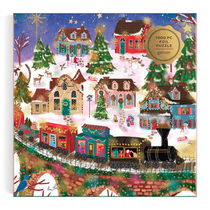 The Joy Laforme Twinkletown Express 1000 Piece Foil Puzzle features a snowy village with decorated houses, reindeer, a gift-filled train crossing a bridge, starry sky, and gold foil accents.