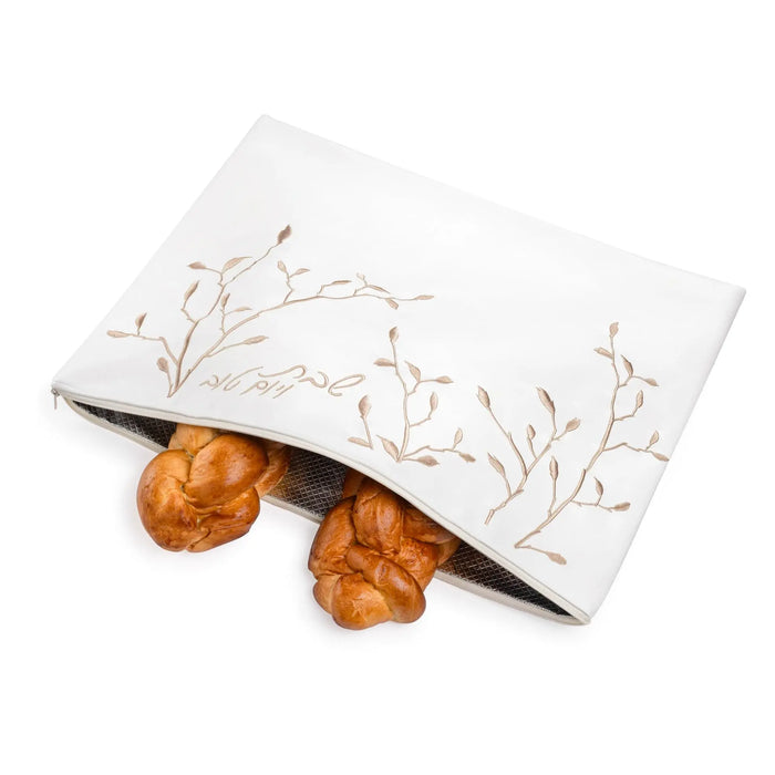 White challah cover with delicate gold leaf embroidery, displayed with two braided challah loaves, elegant Shabbat tabletop accessory.