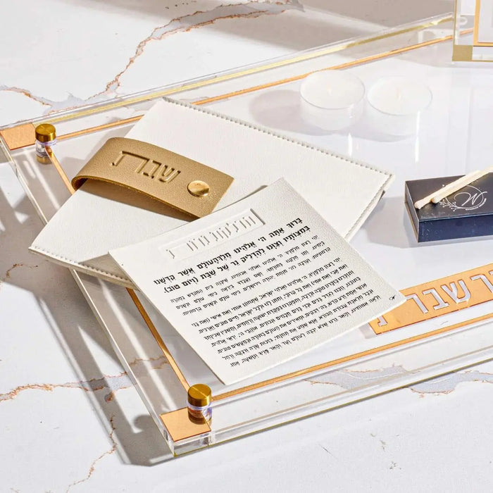 Tan leather Hadlokas Neiros pouch with gold-tone lucite card and candle-lighting instruction card displayed on white surface.