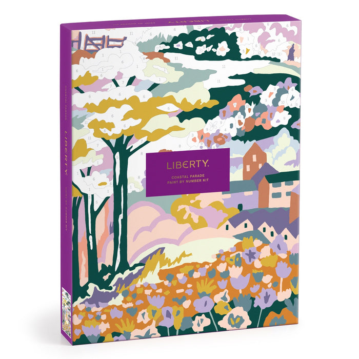 The Liberty London Coastal Parade 9 x 12" Paint by Number Kit features a vibrant box with a stylized landscape of trees, hills, houses, and fields in pastel and bold colors, framed by a purple border and central text.