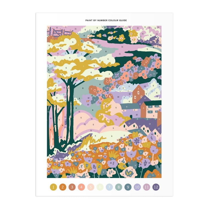 The Liberty London Coastal Parade 9 x 12" Paint by Number Kit features a pastel landscape of trees, hills, houses, and flowers, with numbered sections matching the included color guide.