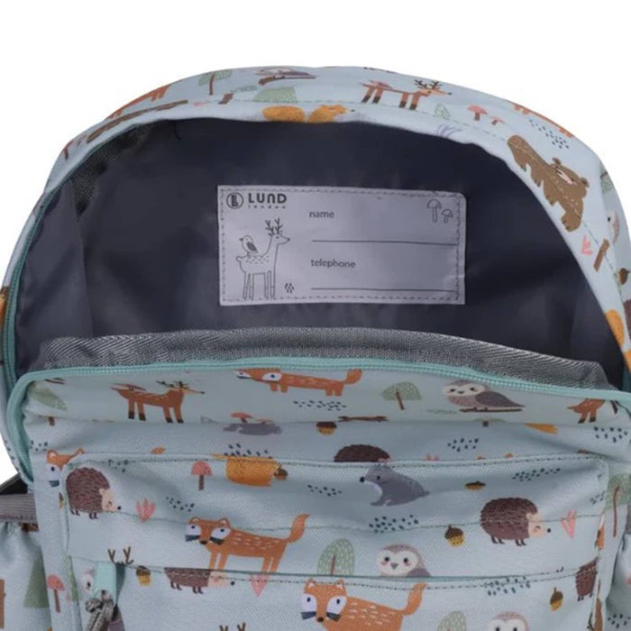 A close-up of a light blue backpack with a woodland animal print, showing the interior lining and a fabric label labeled LUND.