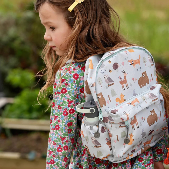 Child wearing a backpack with animal patterns outdoors.