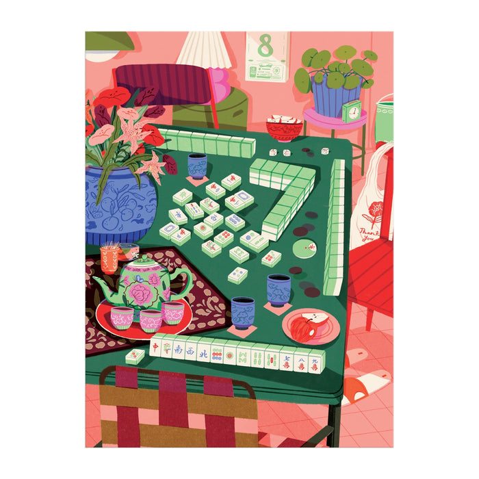 The Mahjong Social 1000 Piece Puzzle by Paige Jung features a vibrant scene of a Mahjong game on a green table with teacups, floral accents, scattered tiles, and cozy room decor for an inviting atmosphere.