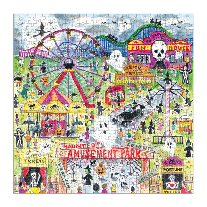 The Michael Storrings Haunted Amusement Park 500 Piece Puzzle features a vibrant Halloween scene with costumed visitors, pumpkins, a haunted house, ferris wheel, fortune teller, carnival stands, and festive skull and skeleton decorations.