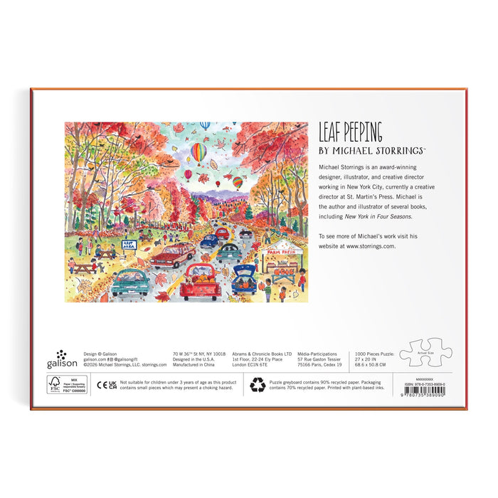 Back of the Michael Storrings Leaf Peeping 1000 Piece Puzzle box shows a vibrant fall scene with cars on a leaf-covered road and autumn trees. Artist details and description are printed on the right. Brand: Michael Storrings.