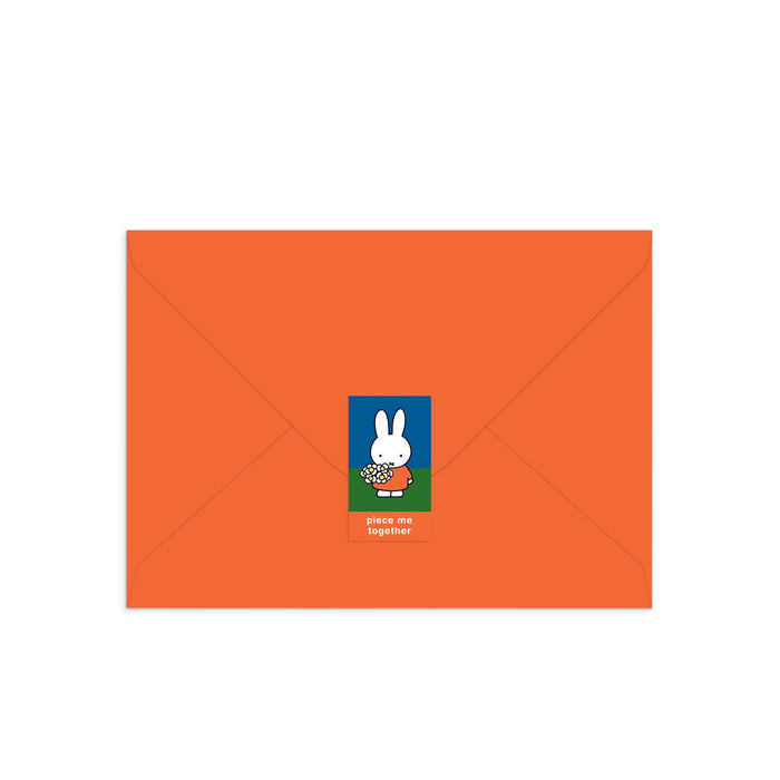 An orange envelope with a Miffy Birthday Greeting Card Puzzle sticker featuring white cartoon bunny Miffy holding flowers and the words "piece me together.