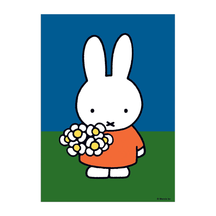 The Miffy with Flowers Greeting Card Puzzle by Miffy features a charming white bunny in an orange dress holding white flowers with yellow centers, standing on green grass against a blue sky.