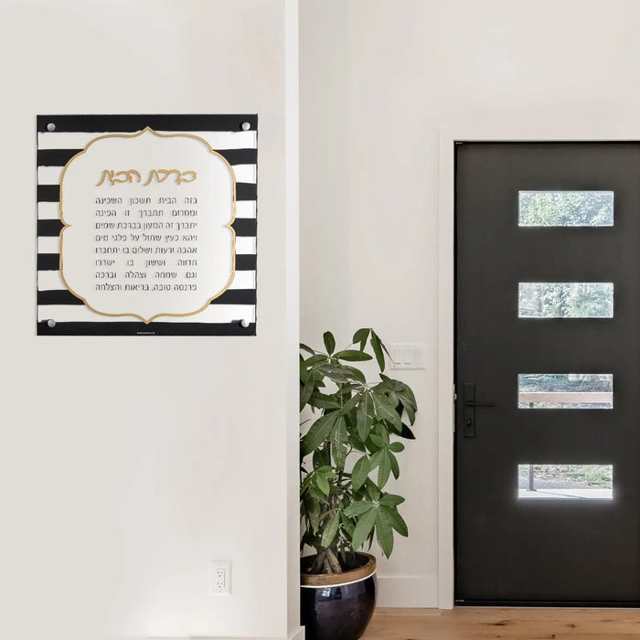Onyx Birchas Habayis wall art with black and white striped frame displayed above a potted plant on white wall.