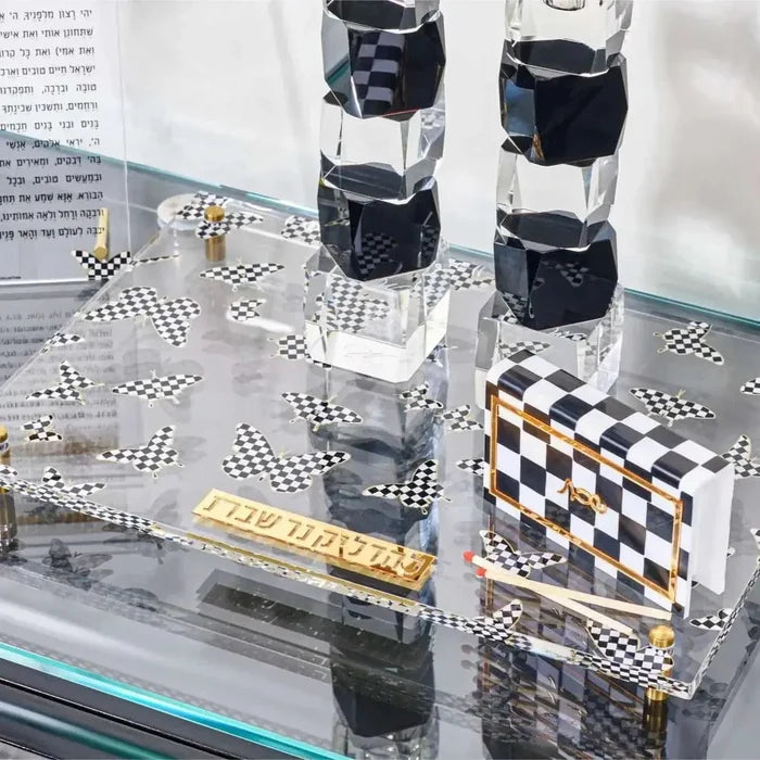 Onyx Butterfly Hadlokas Neiros Set with black and white checkered candlestick holders and matching square bases displayed on glass shelf.