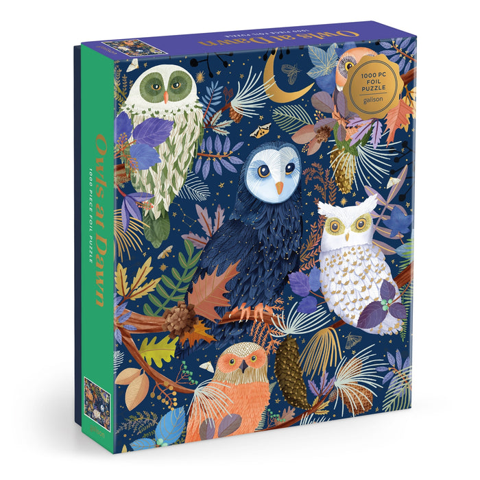 The Owls at Dawn 1000 Piece Foil Puzzle by Mara Penny features colorful owls on branches with leaves, flowers, and pinecones set against a dark blue starry night background.