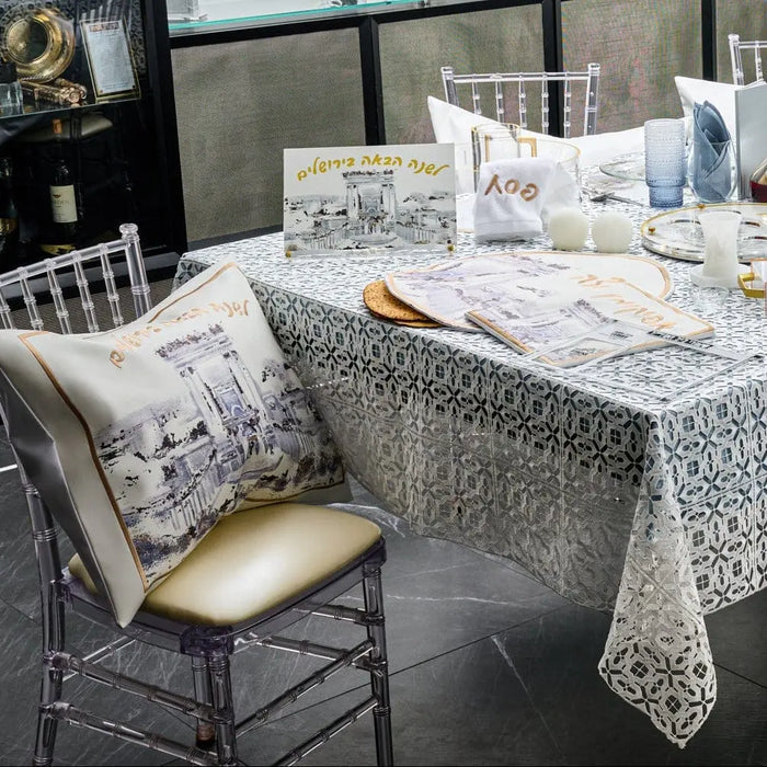Painted Bais Hamikdash Pesach set with silver and gold details on white tablecloth, matching napkins and chair cushion displayed on dark table.