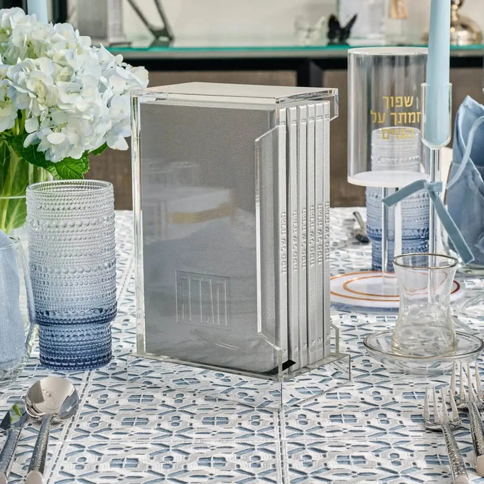 Painted Shabbos Zemiros Bencher set in cream and gold displayed on patterned tablecloth with white flowers and tableware