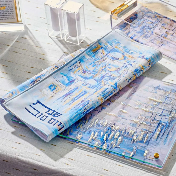 Blue painted leather Yosefa challah cover with intricate Jewish designs, displayed with matching tableware for Shabbat.
