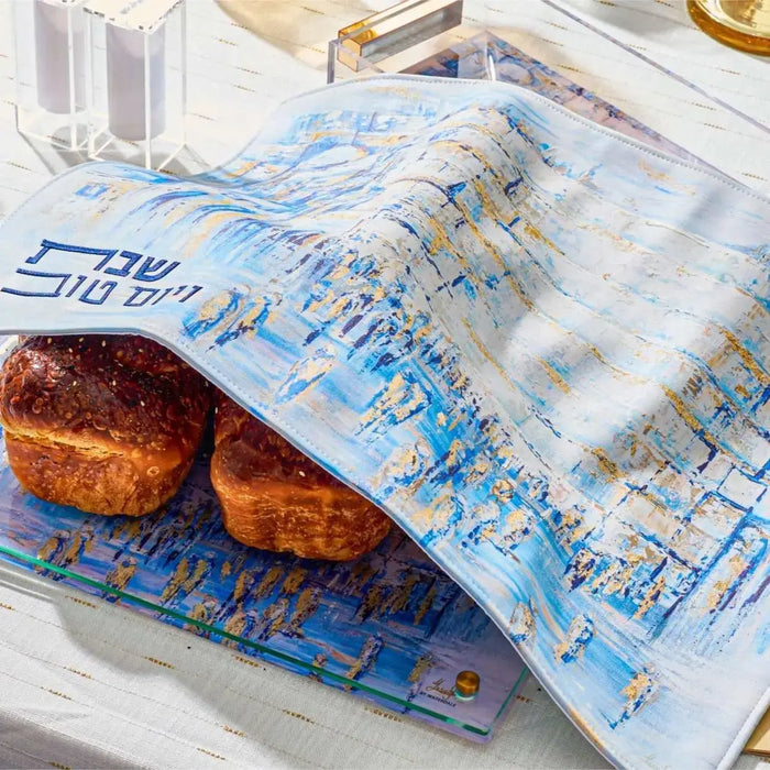 Painted Yosefa challah cover in blue leather with Hebrew text, displayed on table with fresh challah bread for Shabbat.