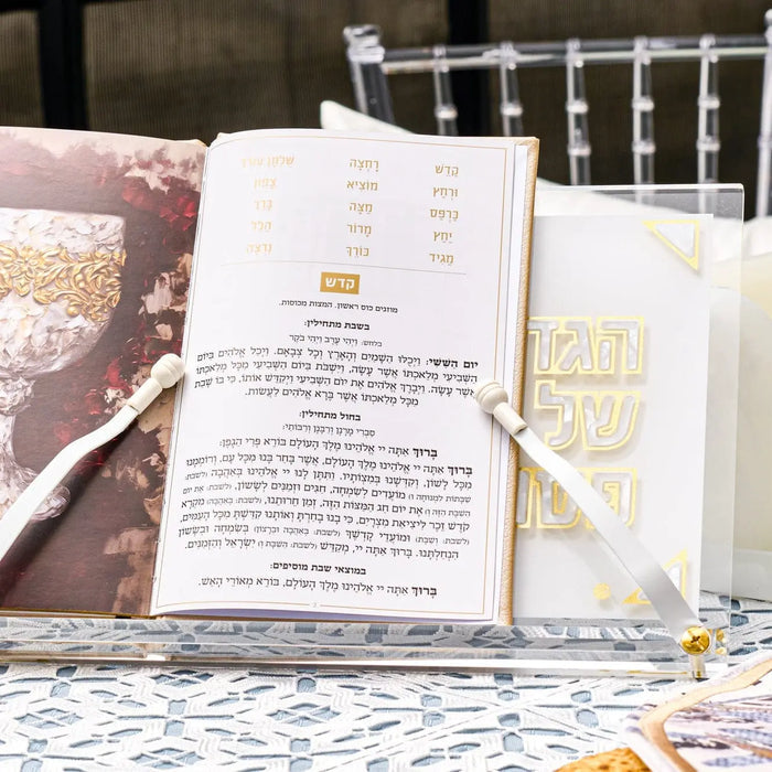 Pearlstone Haggadah stand holding open prayer book on marble table with Pesach tabletop display and decorative elements