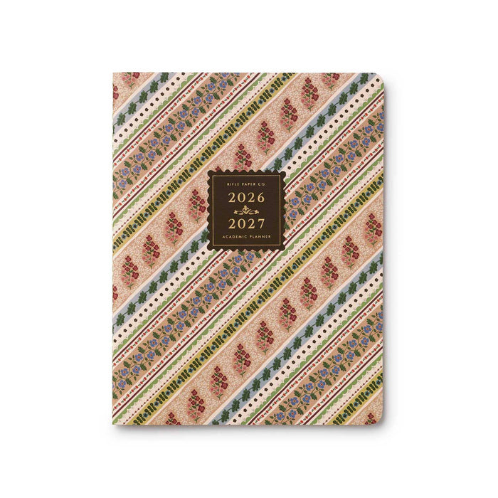A 2026-2027 academic planner with a rose, green, and blue ribbon-striped patterned cover featuring diagonal bands of floral motifs and a central dark brown label.