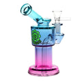 Gradient blue to pink glass bong device with a brand logo on a white background