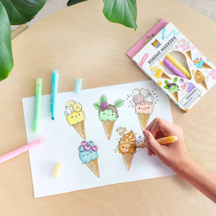 Coloring sheet with ice cream cones and a hand using a marker on a wooden table.