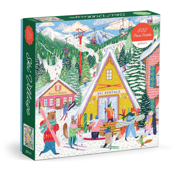 The Emily Taylor Ski Village 500 Piece Puzzle features a vibrant ski village scene with people in winter attire, snow-covered trees, ski lifts, buildings labeled "Ski Rentals" and "Snack Shack," and a scarf-wearing bear carrying skis.